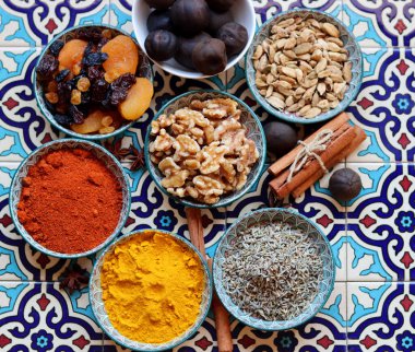 Still life with Traditional oriental spices, nuts, herbs and dried fruit on blue tiled background. Healthy eating concept. 