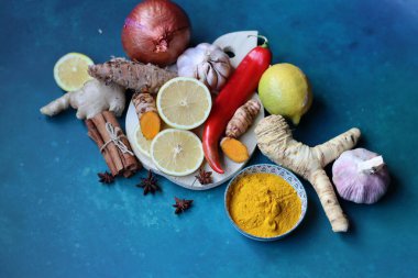 Zencefil, limon, zerdeçal, tarçın çubukları, anason yıldızı, sarımsak ampulü, mavi arka planda fotokopi alanı olan yabanturpu. Soğuk algınlığı ve grip mevsimi. 