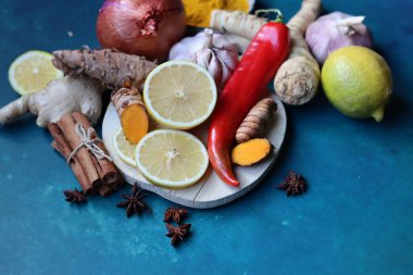 Zencefil, limon, zerdeçal, tarçın çubukları, anason yıldızı, sarımsak ampulü, mavi arka planda fotokopi alanı olan yabanturpu. Soğuk algınlığı ve grip mevsimi. 