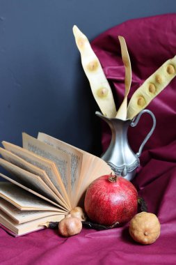 Nar, kitap ve içinde kuru bitkiler olan gümüş vazolarla dolu bir hayat. Fotokopi alanı olan koyu gri bir arkaplan. Okuma konsepti. 