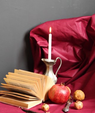 Kitap, nar ve mumla dolu bir hayat Burgonya kumaş arka planda kopyalanmış alan. 