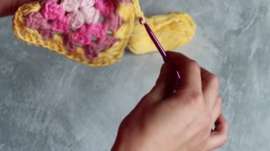 Tığ işi büyükanne meydanını tutan elleri yakın çekim videosu. Örgü ören kadın renkli pamuk süsü. Hobi ve eğlence konsepti. 