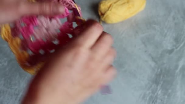 手のクローズアップビデオは かぎ針編みのおばあちゃんの正方形を保持しています カラフルな綿の装飾を編む女性 ホビーとレジャーのコンセプト — ストック動画