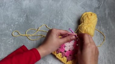 Tığ işi büyükanne meydanını tutan elleri yakın çekim videosu. Örgü ören kadın renkli pamuk süsü. Hobi ve eğlence konsepti. 