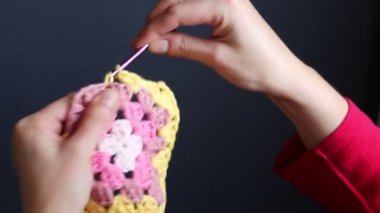 Tığ işi büyükanne meydanını tutan elleri yakın çekim videosu. Örgü ören kadın renkli pamuk süsü. Hobi ve eğlence konsepti. 