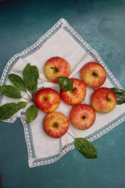 Turkuaz bir arka planda beyaz peçetede elmalar ve metin için yer. Basit kompozisyon hala kırmızı elmayla yaşam. 