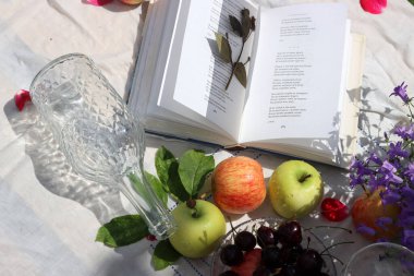 Yaz bahçesinde şarap, elma, kiraz ve çiçeklerle piknik masası. Mevsimlik meyve ve çiçeklerin güzel kompozisyonu. 