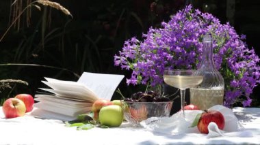 Pastel renkli, çiçekli ve mevsimlik meyveli güzel bir masa. Bahçede bir yaz akşamı