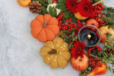 Ilık sonbahar natürmort. Dekoratif balkabaklarıyla, böğürtlenlerle, mumlarla, yapraklarla ve çiçeklerle renkli bir kompozisyon. Masa dekorasyonları fotoğrafı kapatır. Cadılar Bayramı konsepti. 