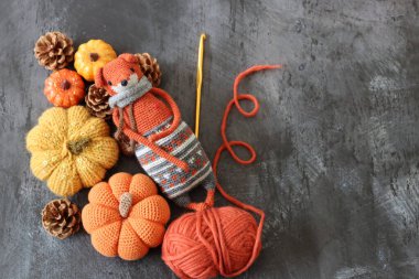 Cadılar Bayramı süslemeleri, balkabaklarıyla örülmüş tilki oyuncakları ve gri arka planda turuncu yün iplik ve mesaj için yer. El yapımı sonbahar hediyesi.. 