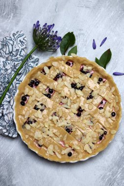 Üzerinde kafes kabuğu olan pişirilmemiş yabanmersinli turta. Yakın plan fotoğraf. Gri desenli arka plan ve fotokopi alanı. Ev yapımı sonbahar pastası.. 