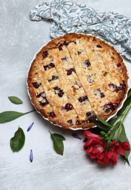 Yaban mersinli ve bademli nefis ev yapımı turta, yaz çiçekleri ve açık arkaplanda yapraklar, taze hamur işi eşyasının en üst görüntüsü. 