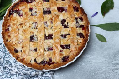 Yaban mersinli ve bademli nefis ev yapımı turta, yaz çiçekleri ve açık arkaplanda yapraklar, taze hamur işi eşyasının en üst görüntüsü. 