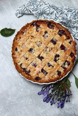 Masada taze pişmiş yaban mersinli örgü turtası. Güzel altın kaplama fotoğraf. Ev yapımı tatlı yuvarlak pasta. Metin için alanı olan açık gri arkaplan. 
