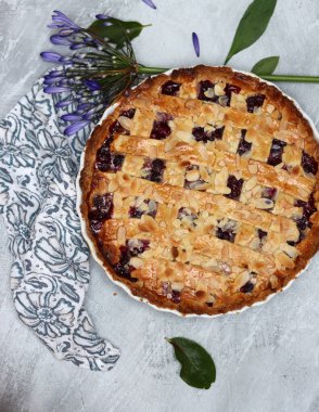 Yaban mersinli ve bademli nefis ev yapımı turta, yaz çiçekleri ve açık arkaplanda yapraklar, taze hamur işi eşyasının en üst görüntüsü. 