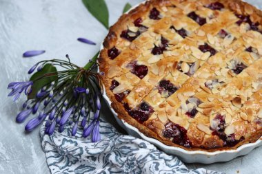Yaban mersinli ve bademli nefis ev yapımı turta, yaz çiçekleri ve açık arkaplanda yapraklar, taze hamur işi eşyasının en üst görüntüsü. 
