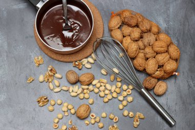 Masadaki ev yapımı çikolata malzemeleri. Fındık ve çikolata yakın plan fotoğraf. Koyu çikolata, şam fıstığı, ceviz ve fındığa karşı koyu arkaplan ve metin için boşluk. 