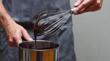Şef çikolatalı ganache yapıyor, yakın plan bir tencereyi tutuyor. Çırpılmış çikolata.