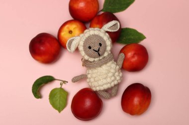 El yapımı Amigurumi oyuncağı açık pembe arka planda yaz meyvesi ve yazı için yeri var. Hobi ve boş zaman aktiviteleri konsepti. 