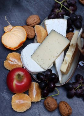 Üzümlü, meyveli ve fındıklı peynir tabağı koyu gri desenli arka plan