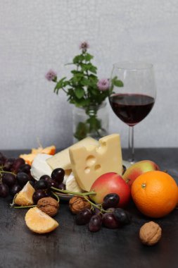Üzümlü, meyveli ve fındıklı peynir tabağı koyu gri desenli arka plan
