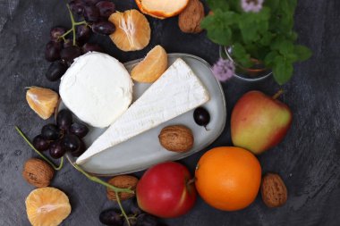 Üzümlü, meyveli ve fındıklı peynir tabağı koyu gri desenli arka plan