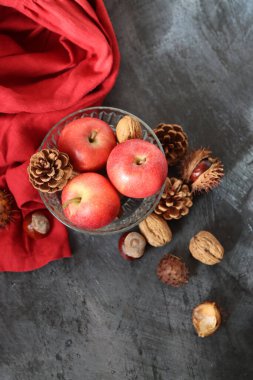 Kestaneli mevsimlik kompozisyon, kırmızı sulu elma ve gri arka planda fındık ve metin için boşluk. Hasat festivali konsepti. 
