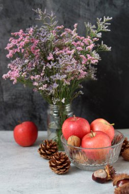 Kestaneli mevsimlik kompozisyon, kırmızı sulu elma ve gri arka planda fındık ve metin için boşluk. Hasat festivali konsepti. 
