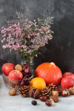 Masanın üzerinde rahatlatıcı yemek malzemeleri var. Balkabağı, elma, fındık ve çiçeklerle dolu renkli bir hayat. Sonbahar hasat konsepti. 