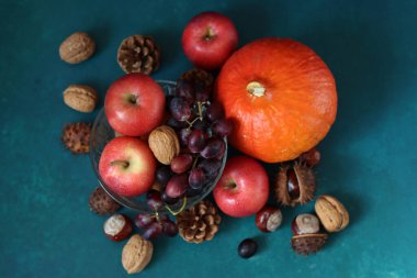 Masanın üzerinde rahatlatıcı yemek malzemeleri var. Balkabağı, elma, fındık ve çiçeklerle dolu renkli bir hayat. Sonbahar hasat konsepti. 