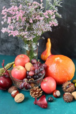Masanın üzerinde rahatlatıcı yemek malzemeleri var. Balkabağı, elma, fındık ve çiçeklerle dolu renkli bir hayat. Sonbahar hasat konsepti. 