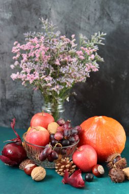 Masanın üzerinde rahatlatıcı yemek malzemeleri var. Balkabağı, elma, fındık ve çiçeklerle dolu renkli bir hayat. Sonbahar hasat konsepti. 