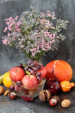 Masanın üzerinde rahatlatıcı yemek malzemeleri var. Balkabağı, elma, fındık ve çiçeklerle dolu renkli bir hayat. Sonbahar hasat konsepti. 