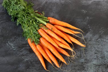 Masasında yeşil yapraklar olan taze havuçlar. Organik çiftlik sebzeleri.. 