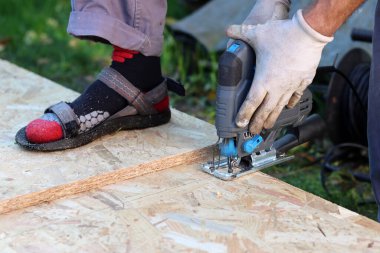 Marangoz tahta kesmek için yapboz kullanıyor. Bahçede tahta kesmek için yapboz kullanan bir işçi.