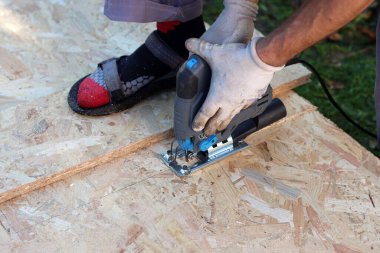 Marangoz tahta kesmek için yapboz kullanıyor. Bahçede tahta kesmek için yapboz kullanan bir işçi.