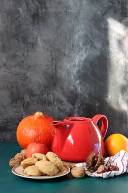 Kırmızı çaydanlık, bir fincan çay, balkabağı, fındık ve kurabiyeyle sonbahar sakin bir hayat. Sıcak sonbahar yemekleri. 