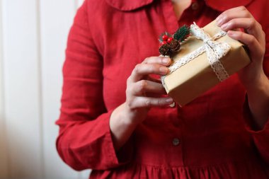 Kadın eli hediye kutusunu tutuyor. Yakın çekim fotoğrafı. Kırmızı elbiseli kadın hediye paketliyor.. 