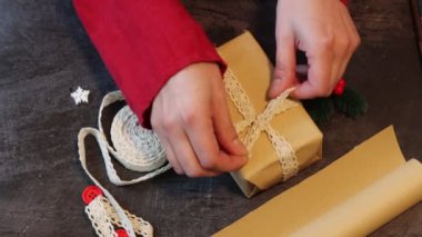 Noel hediyesi dekore eden bir kadın. Noel hediye kutusunu saran eller. Noel için hazırlanılıyor.