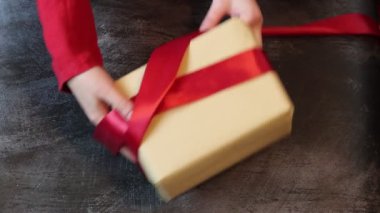 Kırmızı elbiseli bir kadın hediye kutusuna kırmızı kurdele bağlıyor. Noel hediyesi dekorasyon konsepti. 