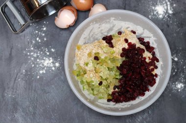 Kızılcık turtası yapmak için gerekli malzemeler - yumurta, un, şeker, fındık, gri arka planda kuru üzüm