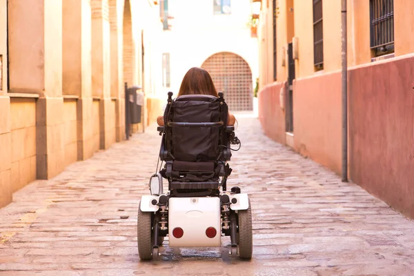 이동성 저하되고 가작은 장애인 여자가 뒷모습으로 보이는 도시의 거리를 휠체어를 — 스톡 사진