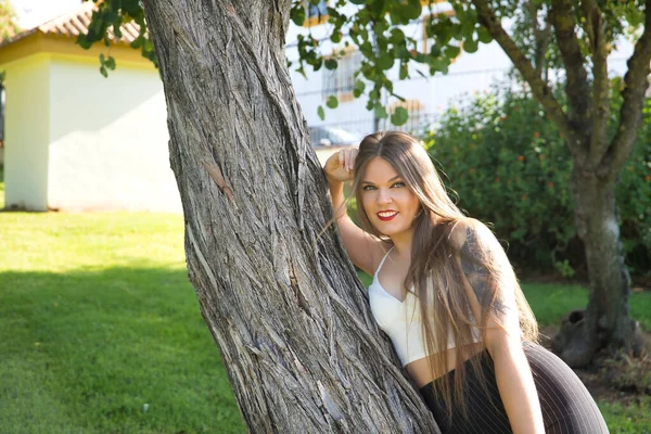 美丽的年轻女子 金发碧眼 阳光灿烂的一天 靠着树干在室外公园里 概念美 — 图库照片