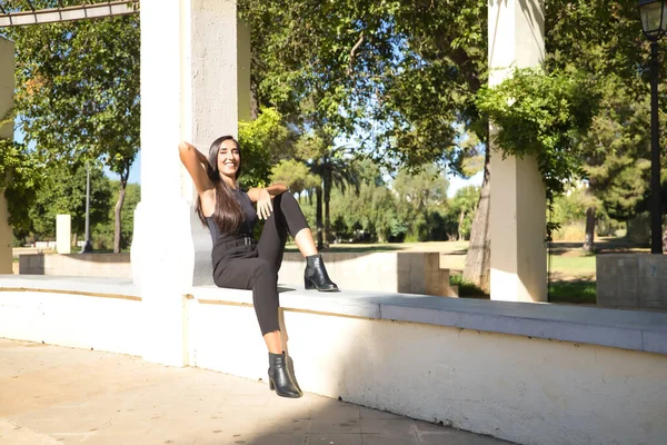 Mujer Joven Morena Delgada Vestida Negro Sentada Banco Sonriendo Felizmente —  Fotos de Stock