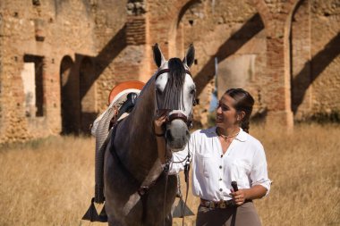 Young and beautiful woman with her horse, resting with him, caressing him, happy in the countryside. Concept horse riding, animals, dressage, horsewoman, care, love.