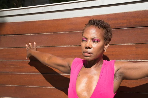 非洲裔美国妇女的画像 身穿粉色T恤 严肃的姿势和张开的胳膊 靠着木板做的背景 赋予概念权力 — 图库照片