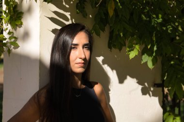 Young woman, brunette, slender and dressed in black, concentrated and thoughtful receiving the sun's rays. Concept beauty, fashion, thinking, concentration, sunbathing.