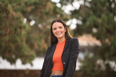Pretty young woman with straight brown hair, jacket and jeans posing happily looking at the camera. Concept fashion, beauty, trend, millennial.