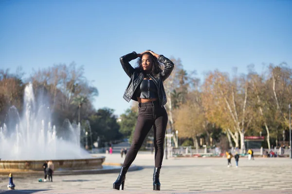 Young, beautiful, Latin and South American woman with leather jacket and top, jeans and platform shoes, touching her hair posing sensual and beautiful. Concept beauty, fashion, diversity, latina.