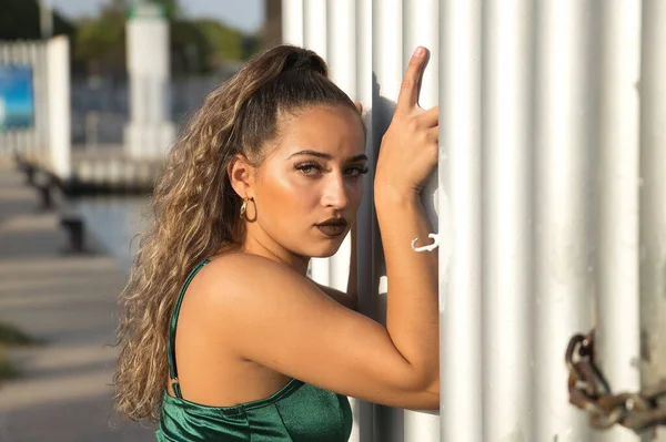 緑の目と大きなまつげ 緑のベルベットの上で 官能的で挑発的な態度でフェンスにしがみつくラテン語とヒスパニック系の女の子 若くて美しい コンセプトの美しさ ファッション — ストック写真